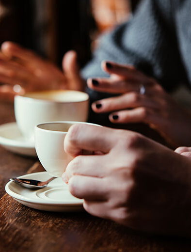 Zwei Menschen trinken Kaffee und unterhalten sich. Dies soll sinnbildlich für ein Beratungsgespräch stehen. Wir bieten Beratung und Unterstützung zum Thema Verschwörungsideologien an.